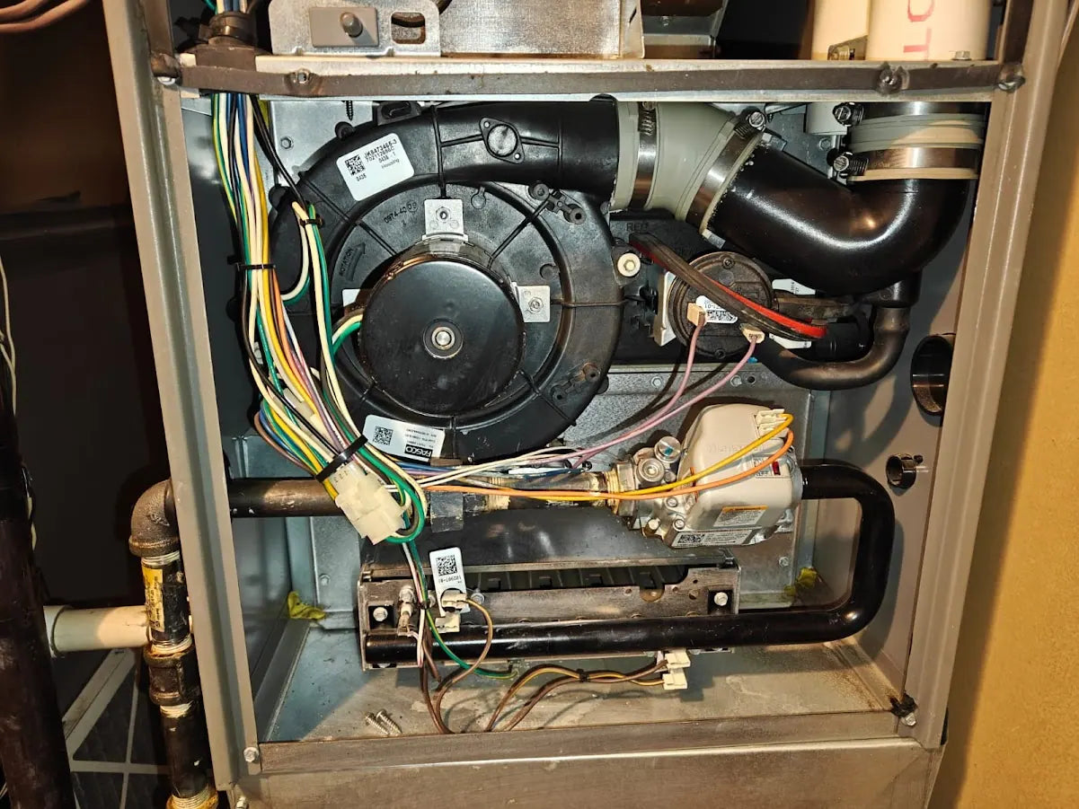 Technician diagnosing an open furnace cabinet in an Edmonton basement